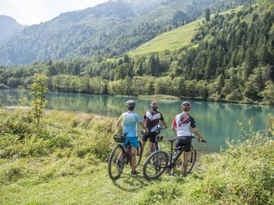 drei Radfahrer stehen am Ufer eines Sees