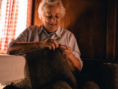 Eine ältere Dame beim Stricken mit Wolle 