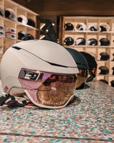 Atomic ski helmets with integrated visors on display in a modern sports shop.