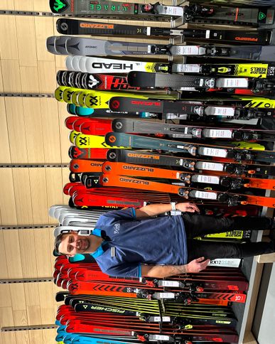 Bründl Mitarbeiter steht vor der Wand mit Blizzard Ski