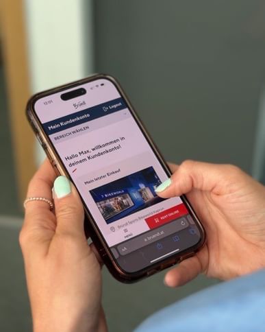 Auf dem Bild sieht man eine Bründl Sports Mitarbeiterin die sich für das Kundenkonto auf ihrem Handy registrieren will.