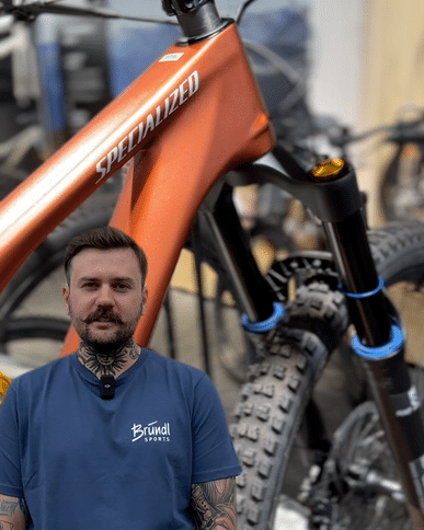 Ein Bründl Sports-Mitarbeiter präsentiert stolz ein leuchtend orangefarbenes Specialized-Mountainbike. Das Bild fängt die Leidenschaft für hochwertige Bikes und authentischen Service ein, und bietet einen spannenden Einblick in die Welt des modernen Radsports.