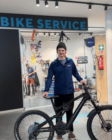Bründl Sports employee stands with a mountain bike in front of the Bründl Sports bike workshop