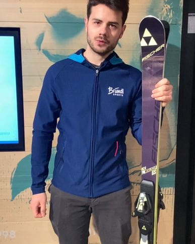 Der Mitarbeiter von Bründl Sports hält ein paar Ski im Hand und erklärt wie der Bringerbonus funktioniert