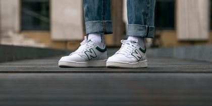 Man sieht neue weiße New Balance Sneakers 