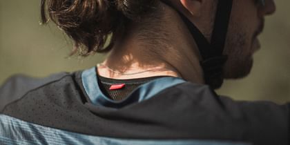 Close-up of the neck of a cyclist wearing a helmet and a breathable performance shirt with a "transtex®" label.