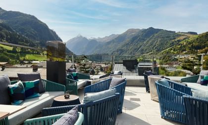 Die stilvolle Dachterrasse mit gemütlichen Loungemöbeln bietet einen atemberaubenden Panoramablick auf die umliegenden Alpen und das idyllische Tal.