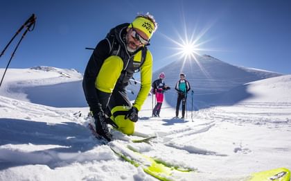 A man dressed in Martini putting on his ski. 