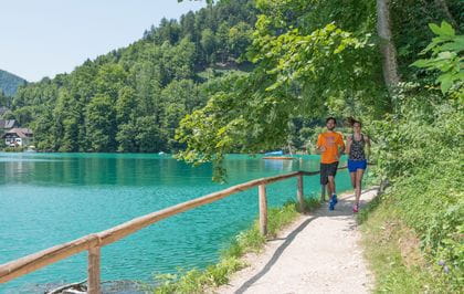 two people are running at the lake "Wolfangsee"