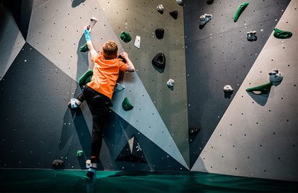 Ein Kind am klettern auf der Boulderwand im neuen Flagshipstore