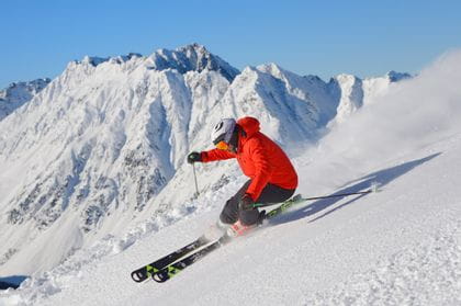 ein Skifahrer fährt rasant einen Hang hinab