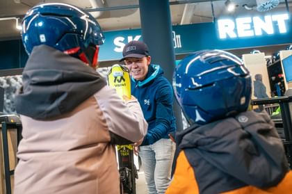 Two children pick up their rental skis in the Bründl Sports Shop 