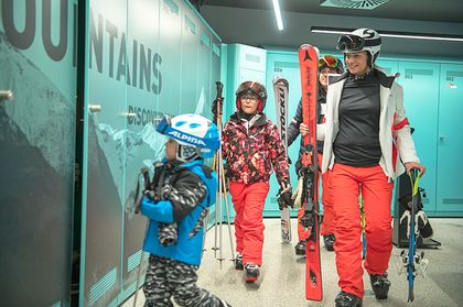Eine Familie geht nach einem Skitag ins Bründl Sports Skidepot und lagert dort ihre Ski und Skischuhe ein 
