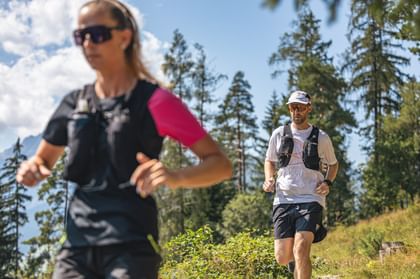 Trailrunning couple running, forest in the background