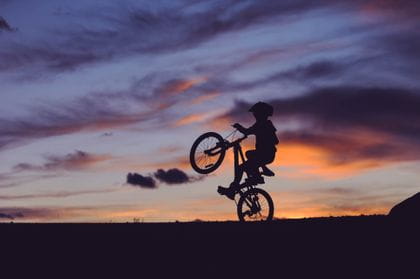 Kid infront of a beautiful sunset with his bike