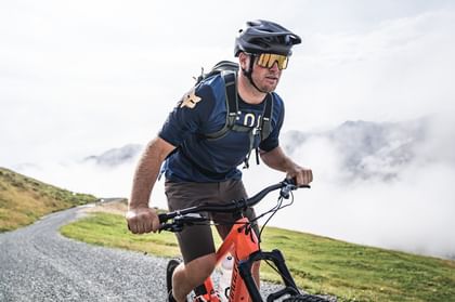 Mountainbiker on the ascent wearing black helmet and sunglasses