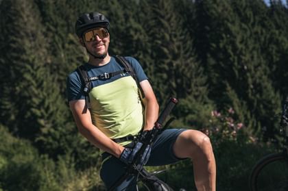 A young man stands atop the mountain after a biking excursion.