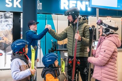 Eine Familie leiht sich mit ihren zwei Kindern Ski bei Bründl Sports