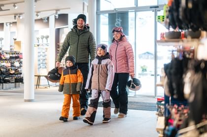 Eine Familie mit zwei Kindern betritt einen Bründl Sports Shop. 