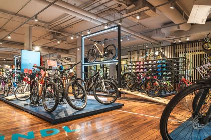 Das Bild zeigt das aufregende Interieur des neuen Bikeworld Shops im Salzburg Outlet. Inmitten des Ladenraums präsentieren sich zahlreiche brandneue Fahrräder in verschiedenen Farben und Stilen.