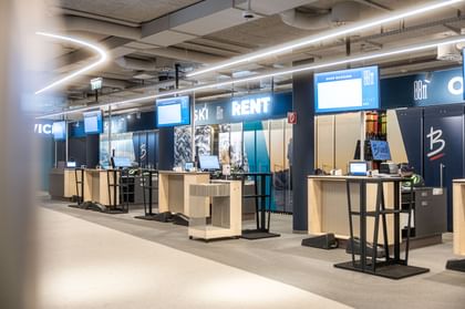 The picture shows a modern ski hire and service area with elegant counters, digital screens and a well-structured layout. The space looks clean and professional and is designed to offer customers a smooth and efficient process.