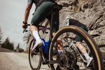 Two cyclists climbing a mountain road in an alpine landscape