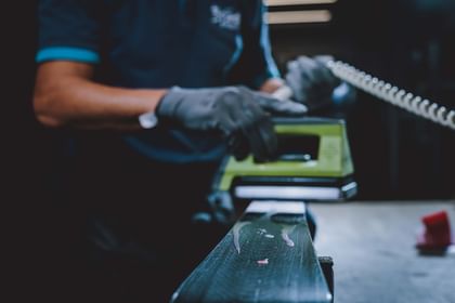 Das Bügeleisen fährt über den Ski und verteilt das heiße Wachs am Belag.