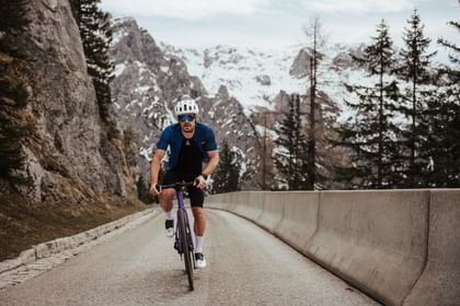 Cyclist riding alone on a mountain road with alpine scenery in the background