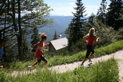 two women are running on a path in the woods