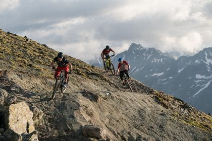 several bikers are riding on a trail track in the mountains