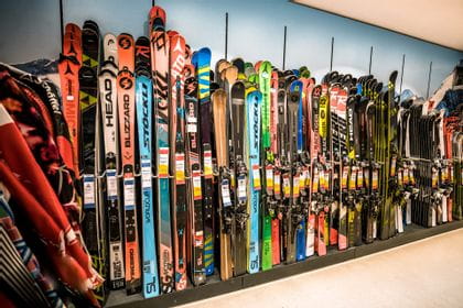 A lot of skis lined up on a wall