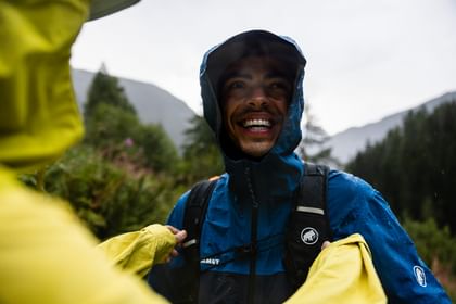 Hiker in Mammut outfit wearing a hood and smiling