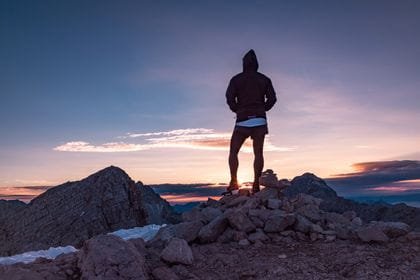 a runner is looking at the sunset in the mountains