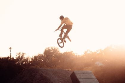 Rider is jumping with his BMX over a kicker