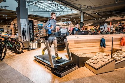 A runner is running on a treadmill which is standing inside the shop