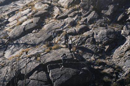 Hikers climbing down a rock wearing Adidas TERREX