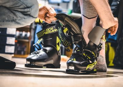 Getting into a skiboot with the help of the shop assistant