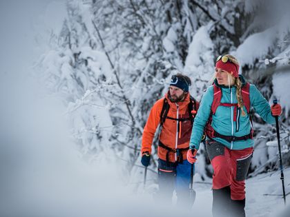 Zwei Personen auf einer Skitour durch eine tief verschneite Winterlandschaft gekleidet in Ortovox 