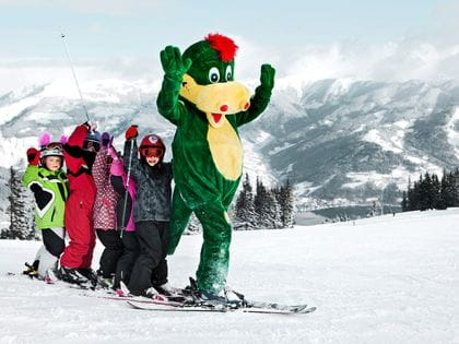 das Bild zeigt einer Kindergruppe beim Skifahren lernen
