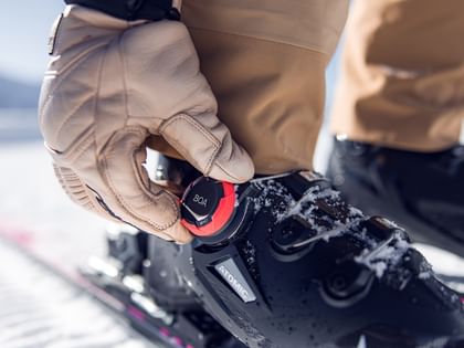 BOA Ski Boots Atomic BOA Atomic Skischuh der von einer Person mit beigen Handschuhen bedient wird.