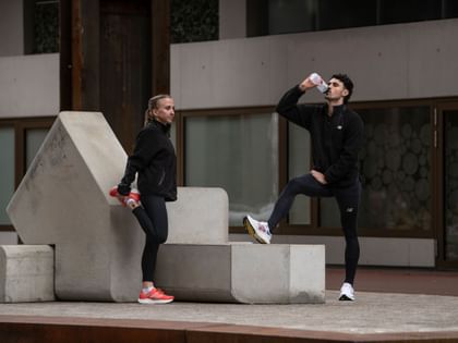 Ein junges Pärchen macht nach dem Joggen eine kurze Pause, um Wasser zu trinken.
