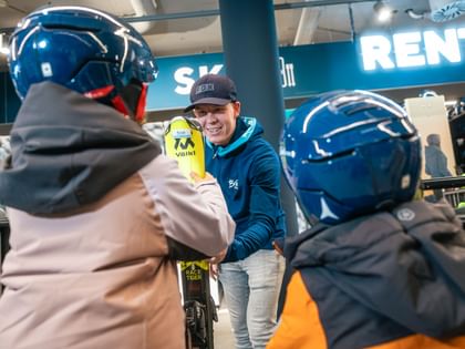 Two children pick up their rental skis in the Bründl Sports Shop 