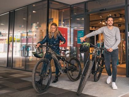 Zwei Menschen mit Rad vor einem Geschäft