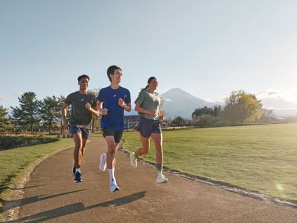 Drei Läufer joggen im Sonnenschein, im Hintergrund Berge