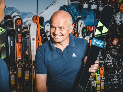 Manfred Rogetzer, Leiter Bründl Sports Racing Service, mit Fischer Ski vor einer Skiwand