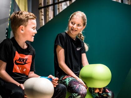 Junge und Mädchen auf zwei Spielfiguren in der Kinderspielecke bei Bründl Sports in Saalfelden