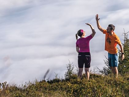 Two hikers exchange a high-five on a grassy hilltop – a moment of shared joy in nature.