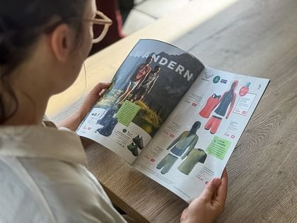 Eine Frau hält das neue Magic Moments Magazin in den Händen und blättert durch. 
