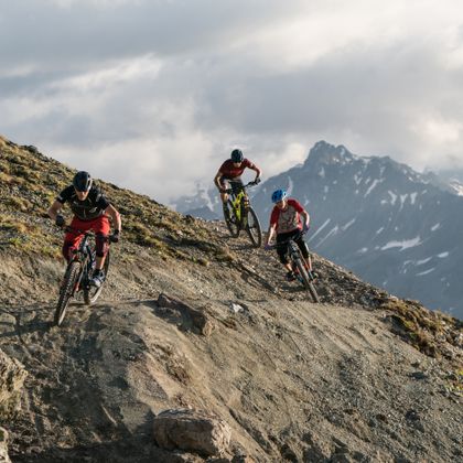 several bikers are riding on a trail track in the mountains
