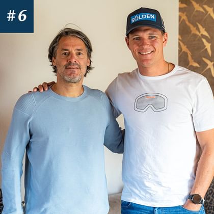 Das Bild zeigt zwei Personen, die lächeln. Der Mann links trägt einen hellblauen Pullover, der Mann rechts trägt ein weißes T-Shirt mit einer Skibrille drauf und eine dunkelblaue Kappe mit dem Logo von Sölden darauf. <br/>Der Mann links heißt Stefan Steinacher und der Mann rechts Thomas Dreßen. 